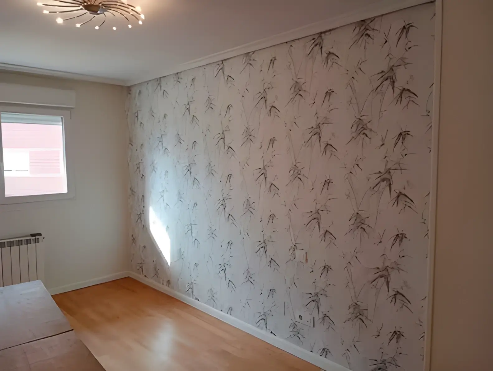 Los Pintores Alcorcón colocando papel pintado en pared de acento de habitación luminosa